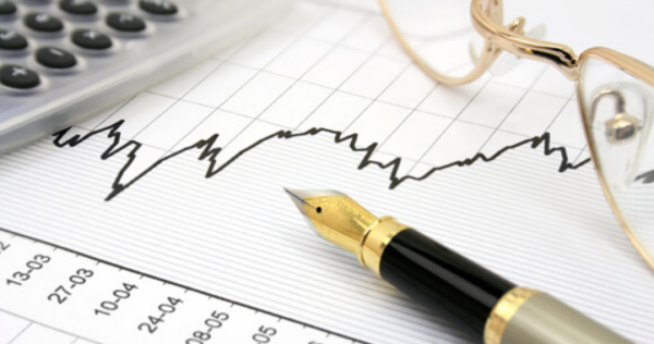 Calculator and pen on financial graph paper.